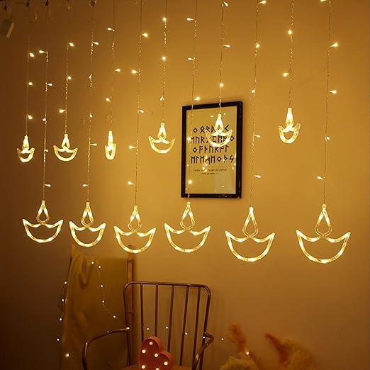 Decorative string lights shaped like candles hanging on a wall with a framed picture below.